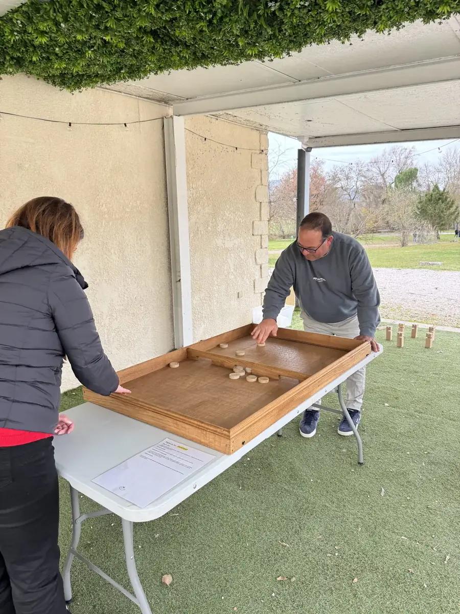 Participants jouant à un jeu de glisse en bois sous un préau