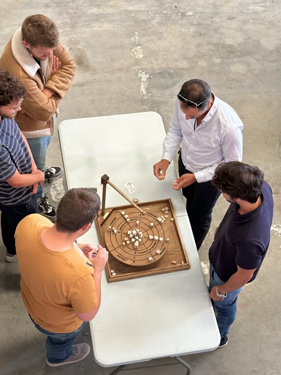 Joueurs autour d’un jeu de labyrinthe en bois